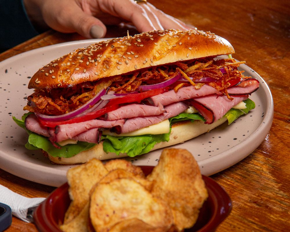 A sub served on a plate with a side of crisps